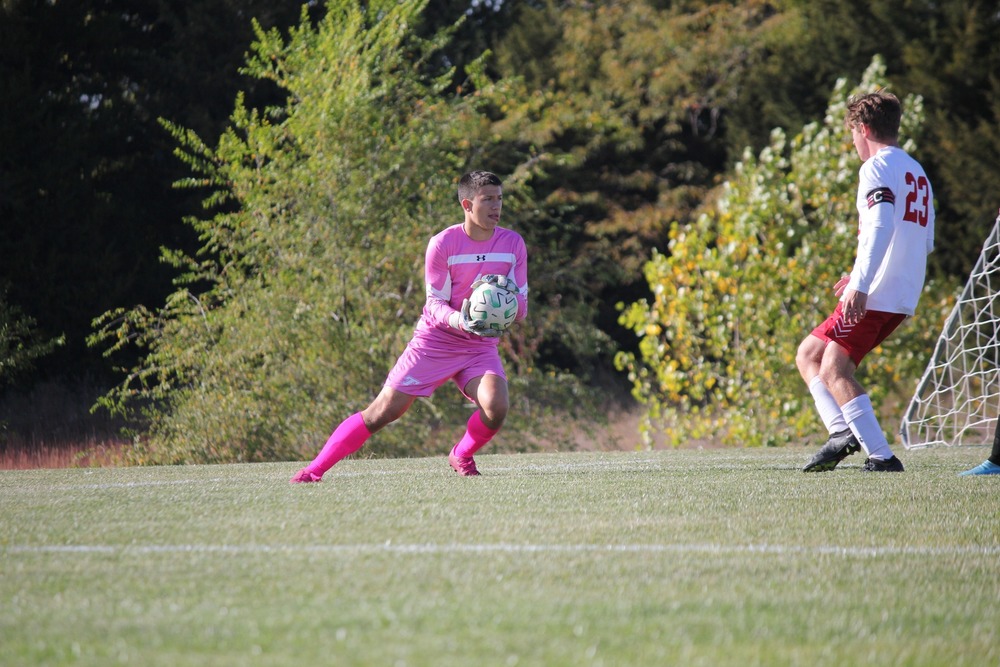 Soccer goalie wearing all pink holds soccer ball on a soccer field
