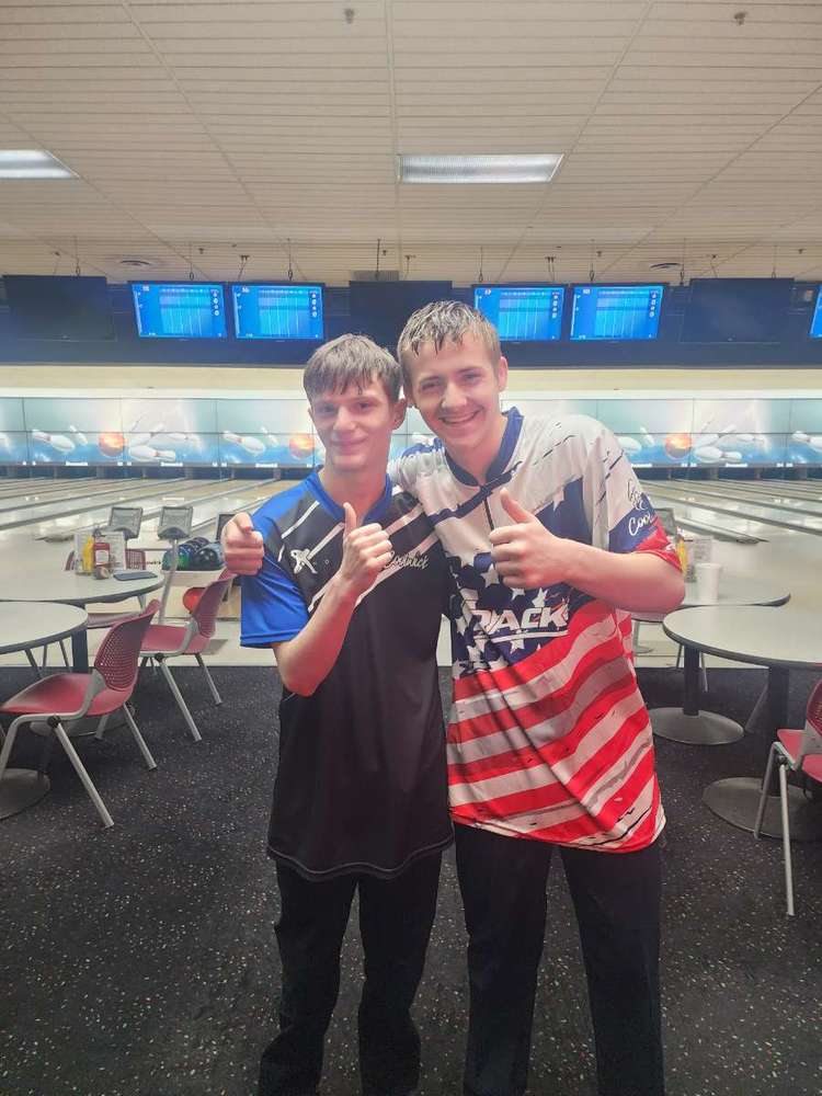 Jacob Smith and his brother Brenden wearing bowling jerseys, standing in front of bowling lanes