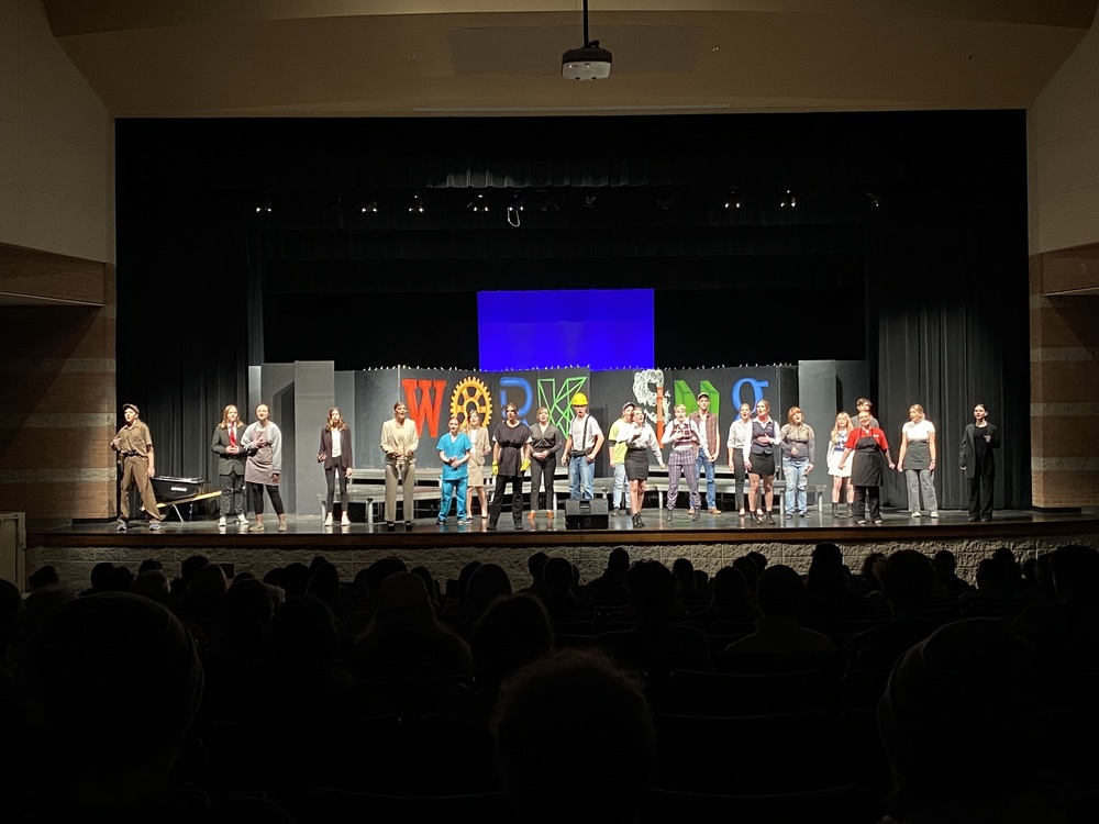 Cast of Working: A Musical appears on stage together wearing costumes portraying various careers