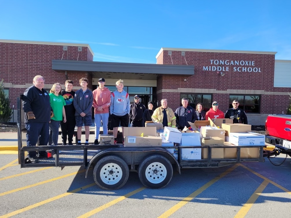 middle school students stand on a flat bed trailer loaded with canned goods