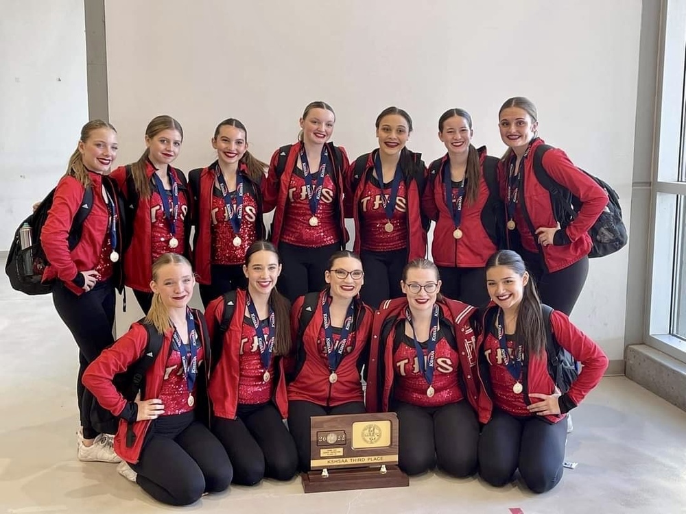 Dance team members in red tops and black pants pose with third place trophy