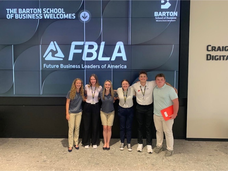 six student wearing business casual clothing stand in front of an FBLA banner 