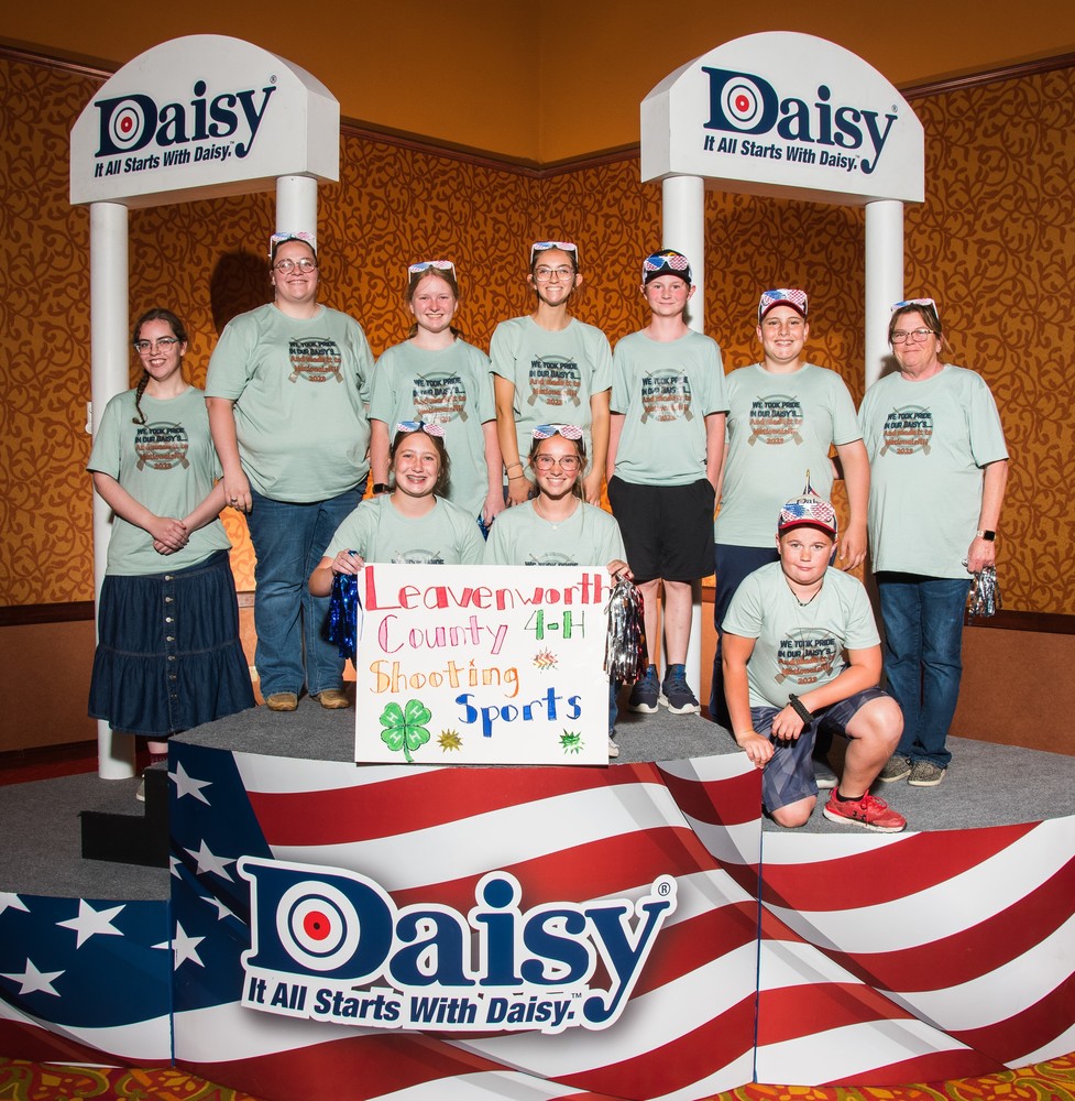 ten members of the club wearing green shirts stand on an American flag themed stage