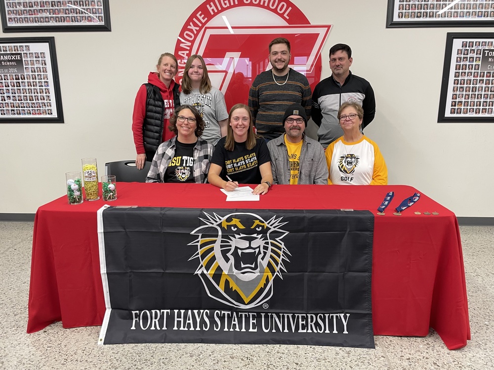 Hayden York Signs with Fort Hays State University golf. Her family members sit beside and stand behind her.