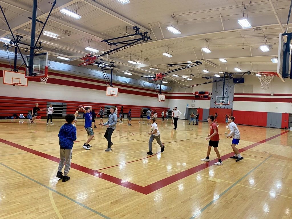 Middle school students play basketball in  a school gymnasium