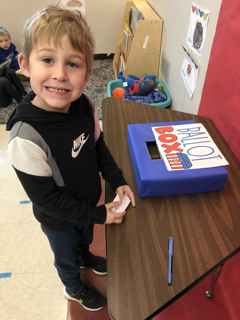 A second grade student smiles while he casts his ballot for his favorite cookie.