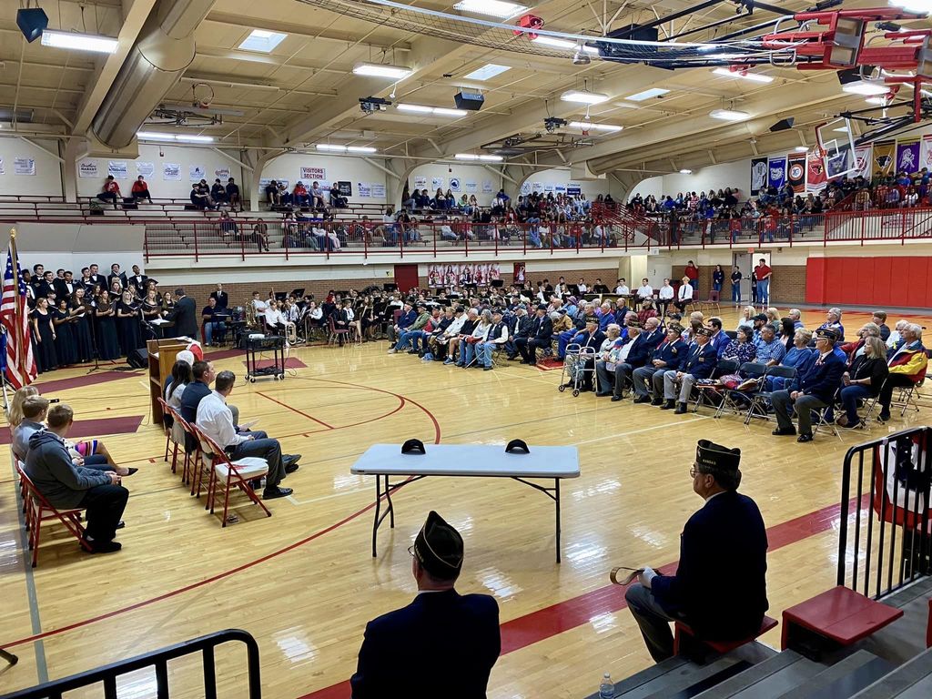 Wide view of high school gymnasium where students, veterans, choir and band and present
