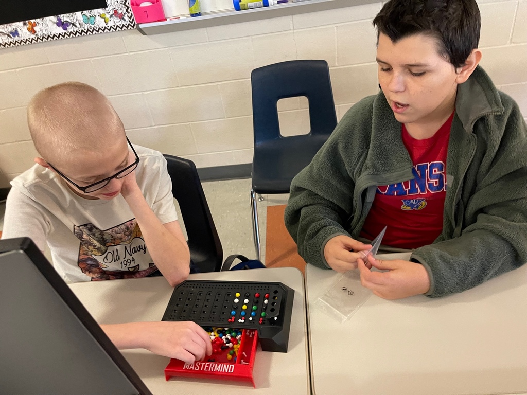Two middle school boys play Mastermind, a code-breaking game for two players.