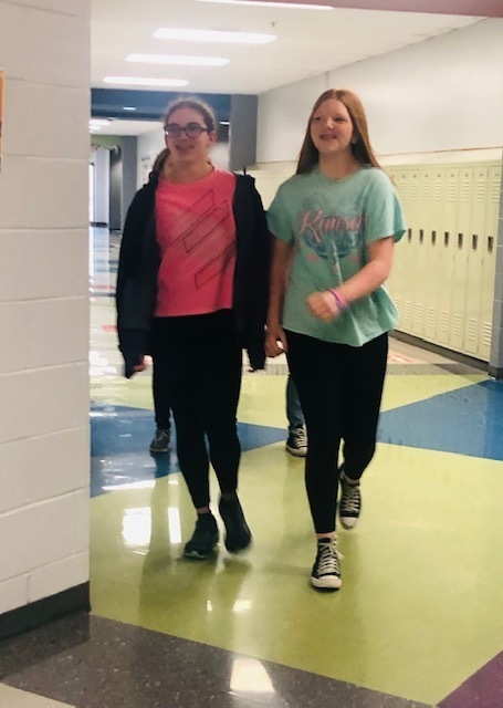 Two middle school students walk down a school hallway