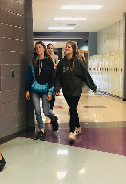 Two middle school students walk down a hallway