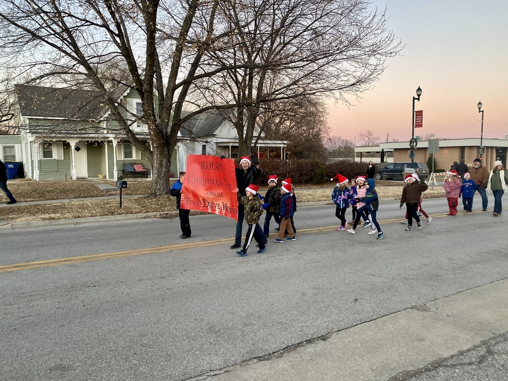 Second grade students carry a red banner in the holiday parade