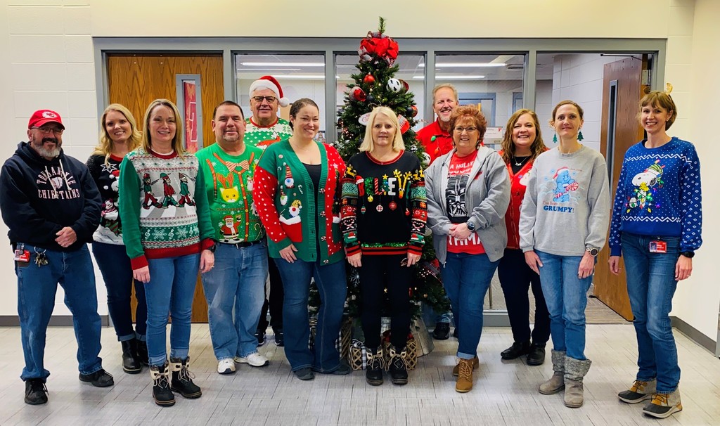 district office staff stand in front of a decorated tree wearing colorful sweaters