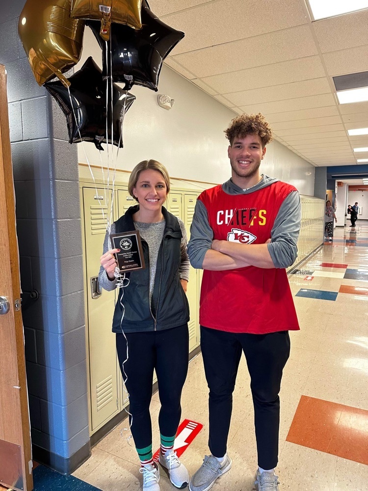 Mrs Deathe holds balloons while standing next to Mr Jackson in the TMS hallway 