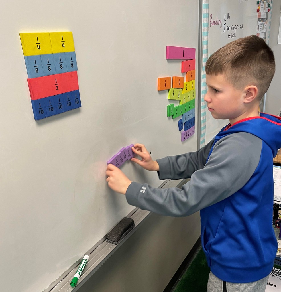 fourth grade student moves foam fraction magnets on a magnetic whiteboard