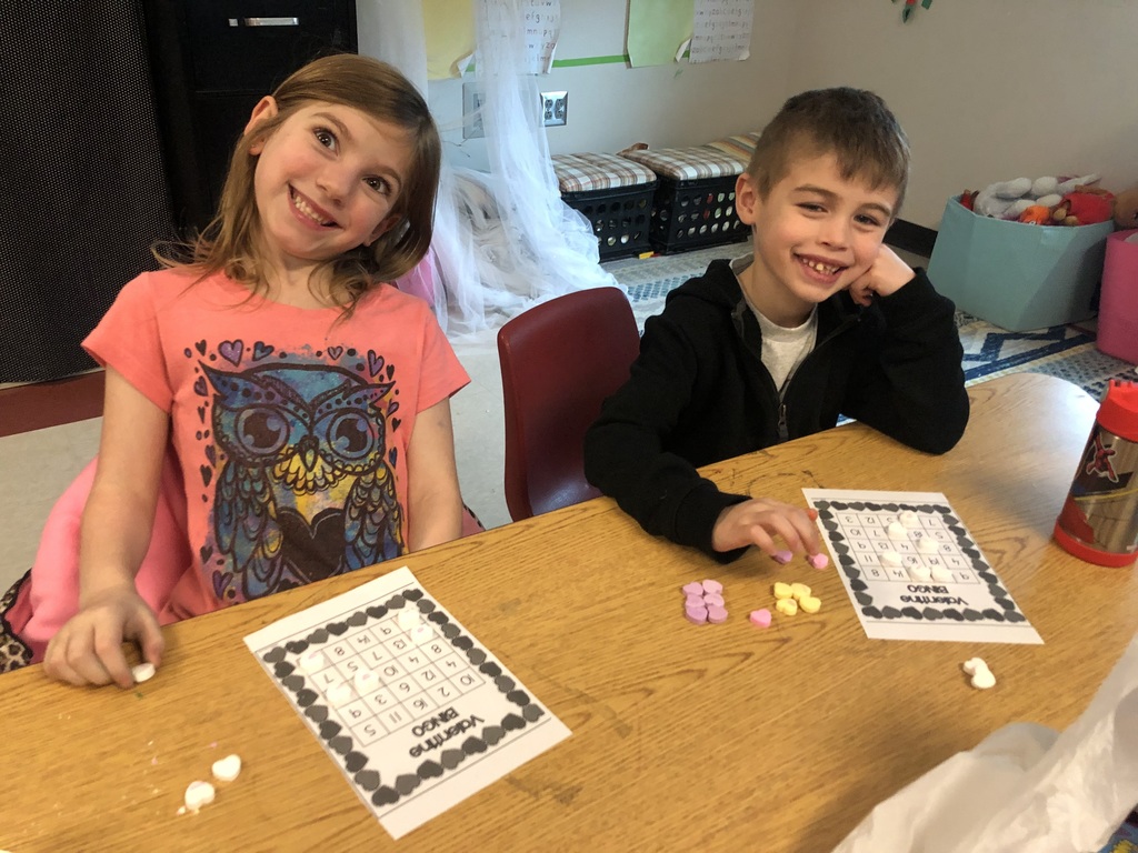 two kindergarten students play Valentine Bingo using conversation heart candy