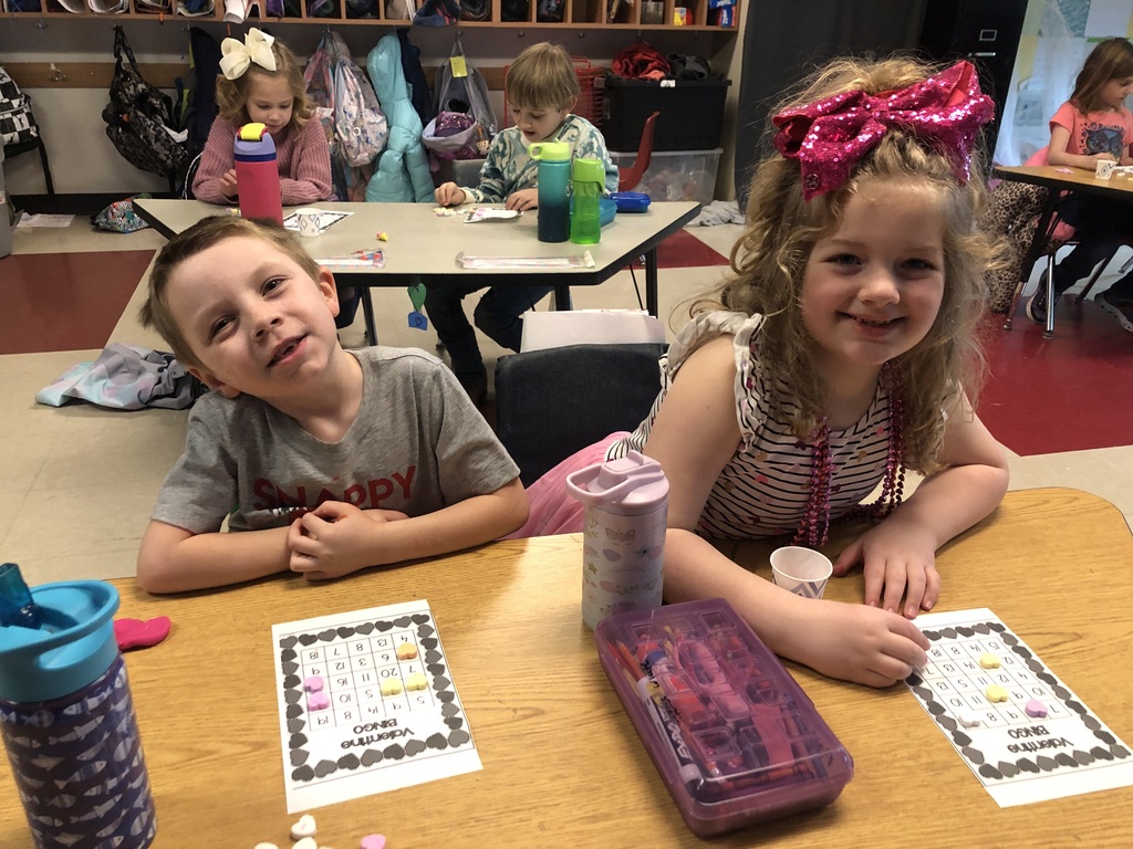 two kindergarten students play Valentine Bingo using conversation heart candy