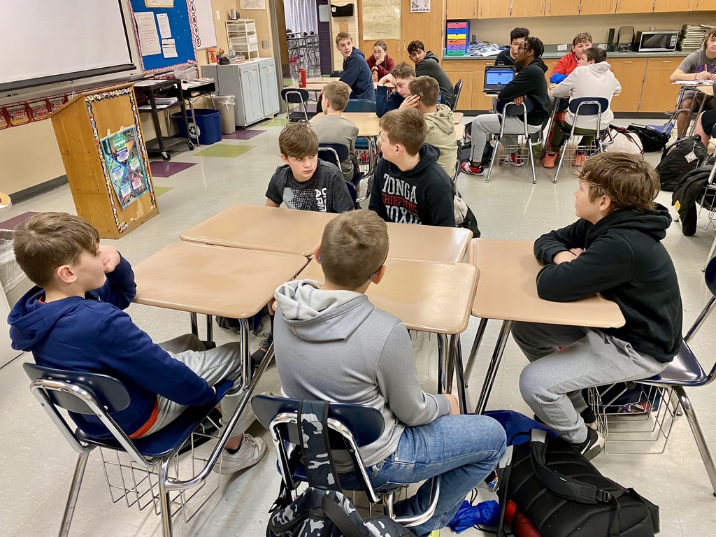 five students sit at a block of five desks