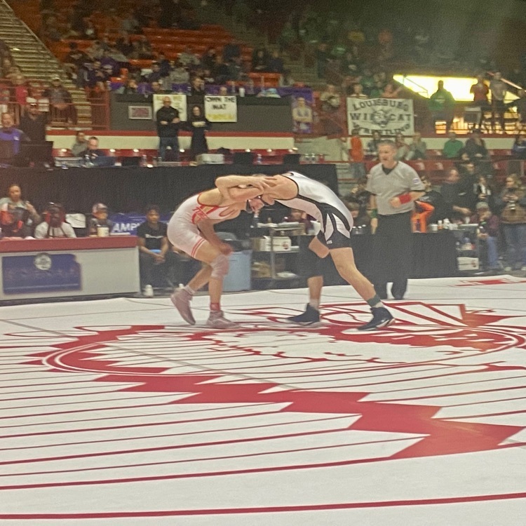 Brady Martin wrestles opening in blue and white on a white mat