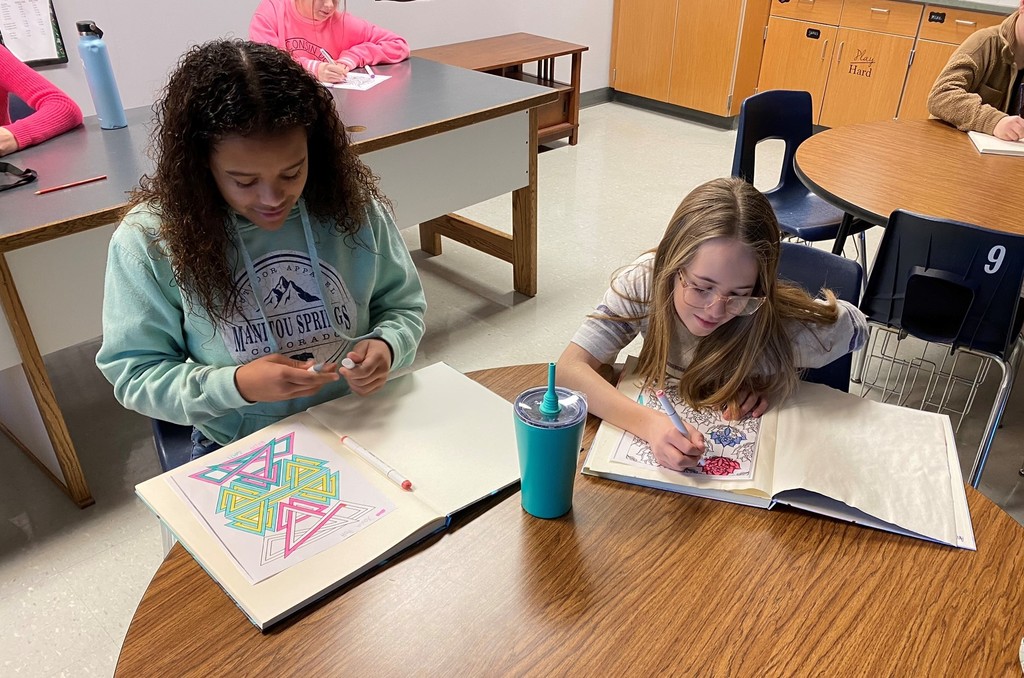 two students color at a round table