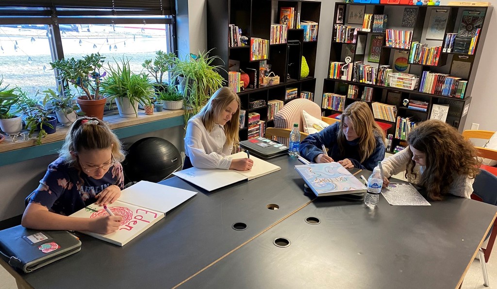 four students sit at a black table coloring