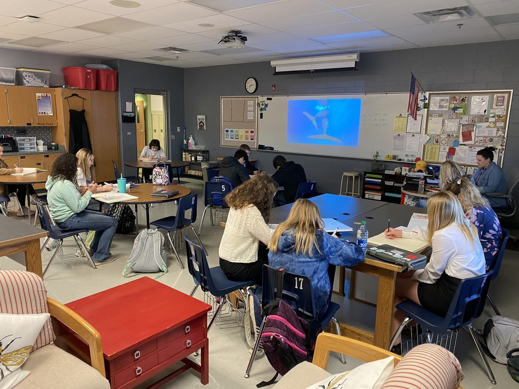 students sit in a classroom while a video of ocean life plays on a projector