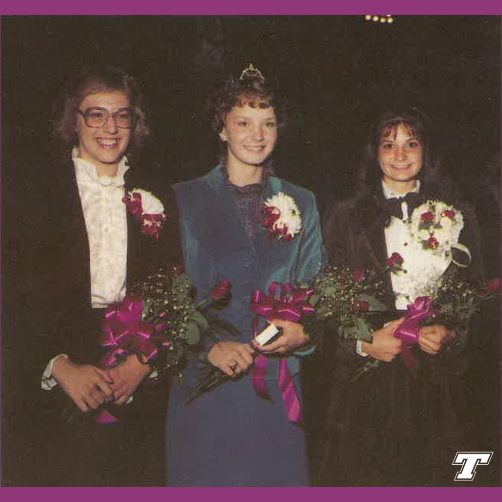 three homecoming court members wearing dresses and holding flowers