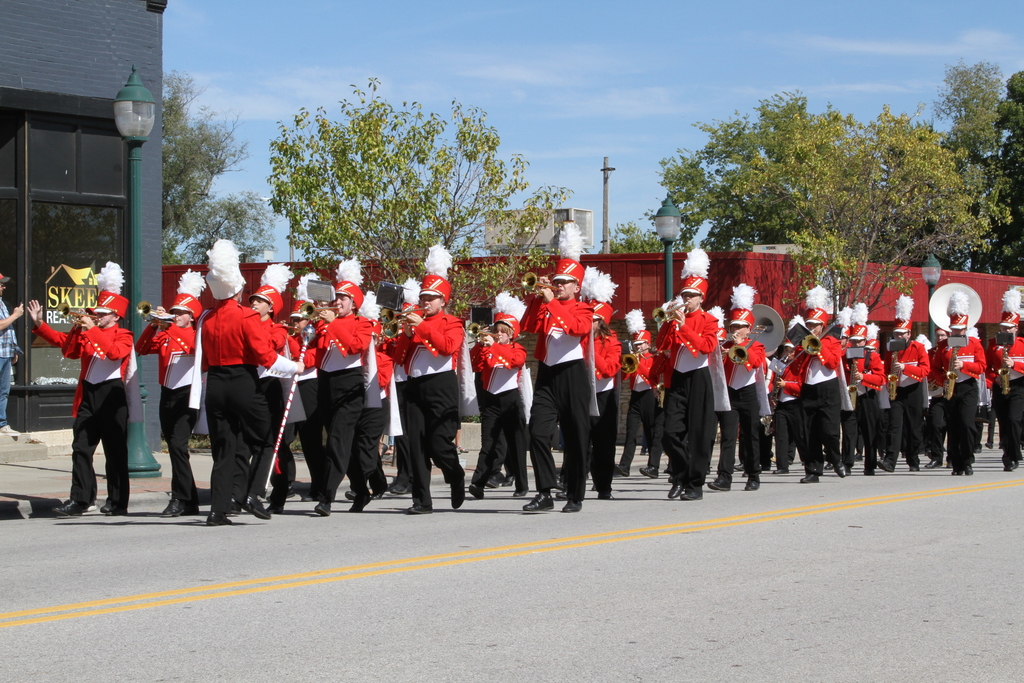 chieftain marching band wearing red uniforms walks down the street