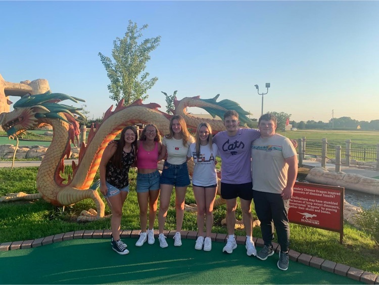 six students stand together on a mini golf course 