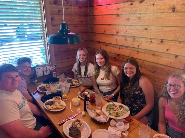 six students sit together at a table in a restaurant